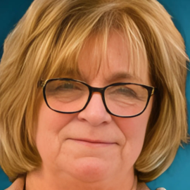 A middle-aged, light skinned woman with honey blond hair and glasses